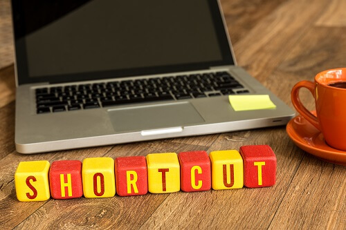 Shortcut written in wooden cubes on an office desk| Featured image for Five Essential Keyboard Shortcuts for Researchers blog for Pacific Transcription.
