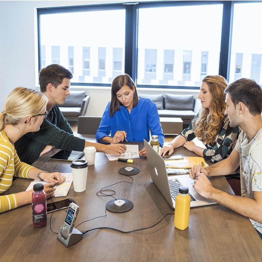 Business people sitting around a large table, with microphones and recording devices | Featured image for How to Achieve Crisp Clear Conference Audio Recording blog for Pacific Transcription.