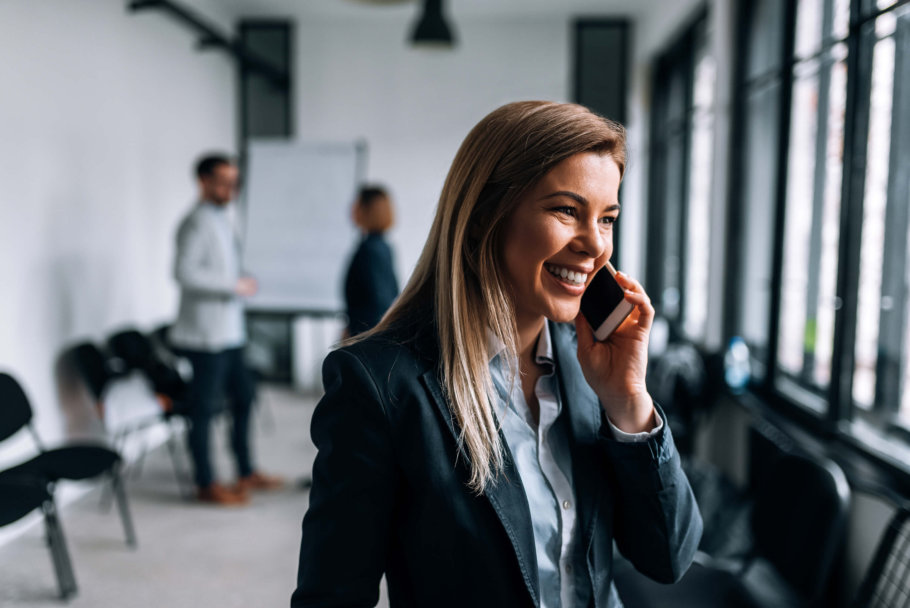 Portrait of a smiling blonde businesswoman talking on a phone during the break from a meeting - best way to record phone interviews / recording phone interviews blog featured image.