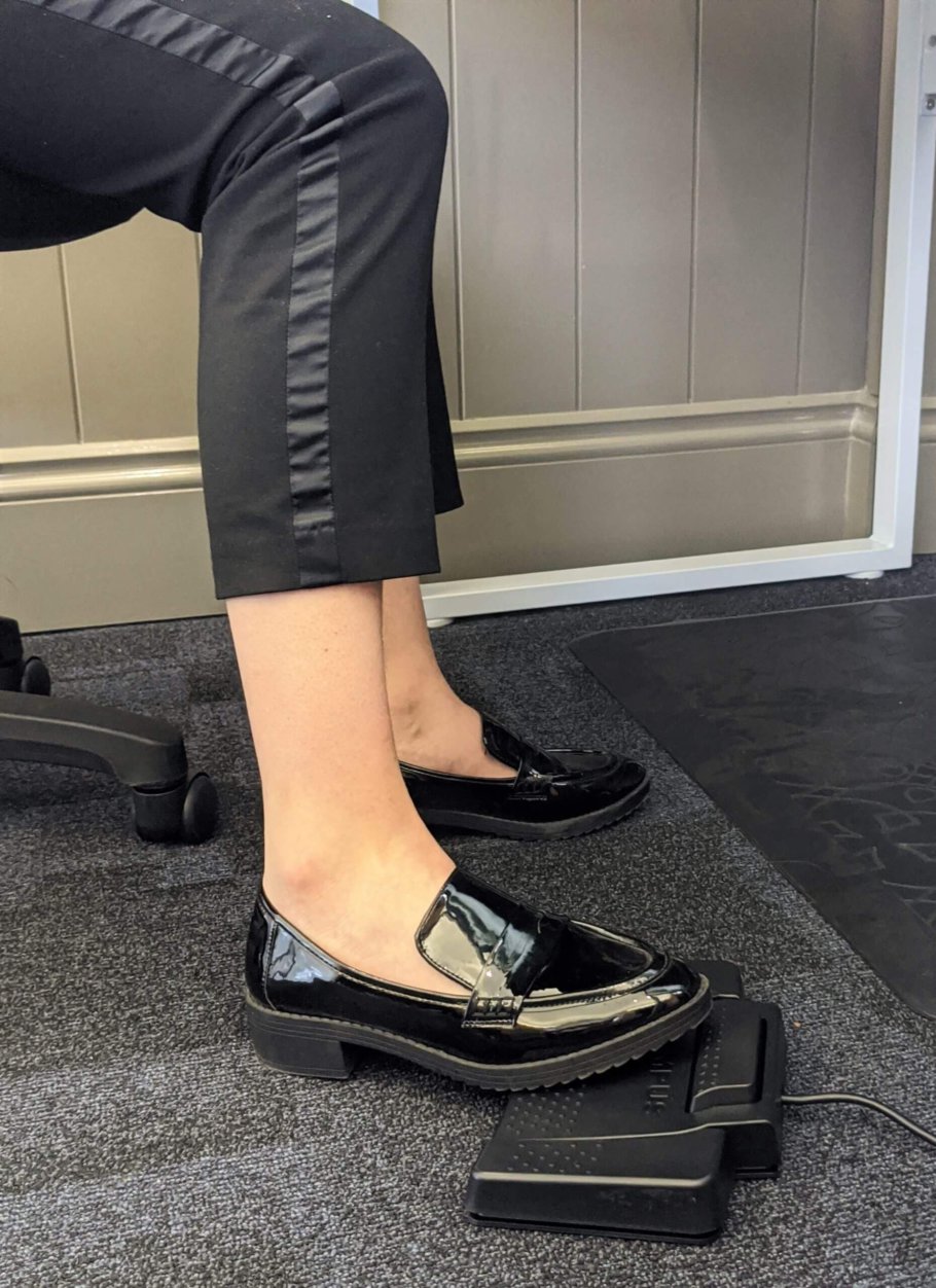 Close-up of a woman using a transcription foot pedal | featured image for Using a Transcription Foot Pedal to Make Work Easier blog for Pacific Transcription.