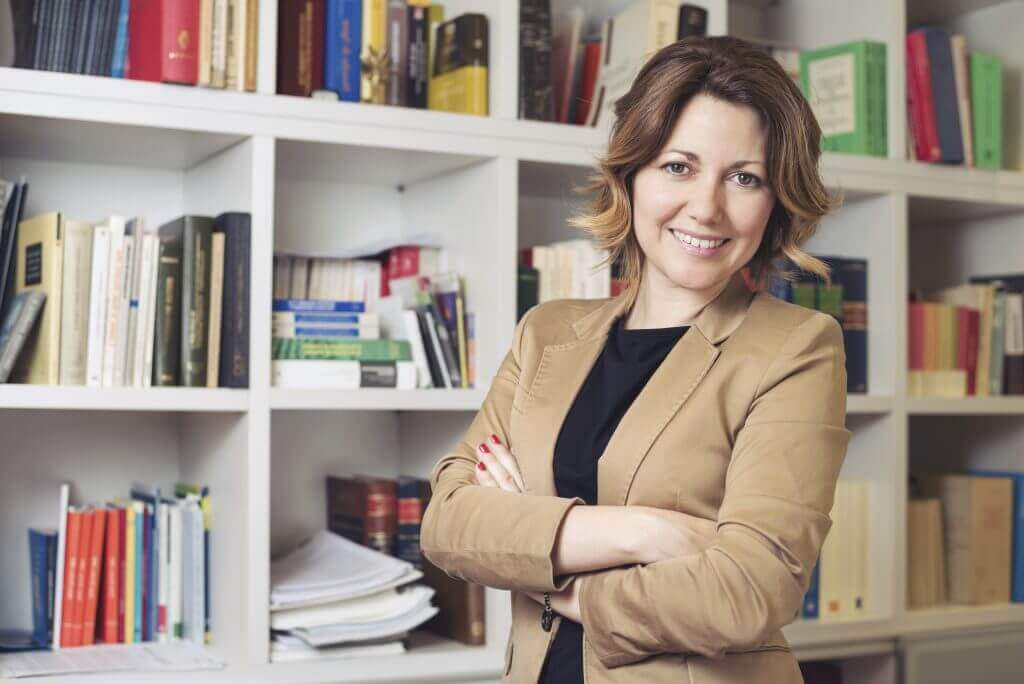 A researcher standing in front of a bookshelf filled with academic materials | Featured image for ATLAS.Ti Transcription services at Pacific Transcription Australia.