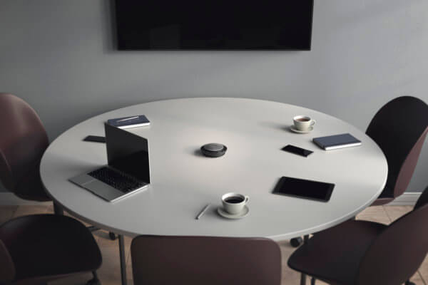 Photo of a round meeting table with smart devices on it | Featured Image for Jabra Speak 750 - Bluetooth Conference Speakerphone Page by Pacific Transcription.